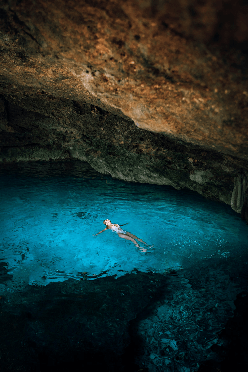 Swimmer floating in a hidden cenote cave